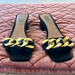 Black heeled slides with gold chain embellishment